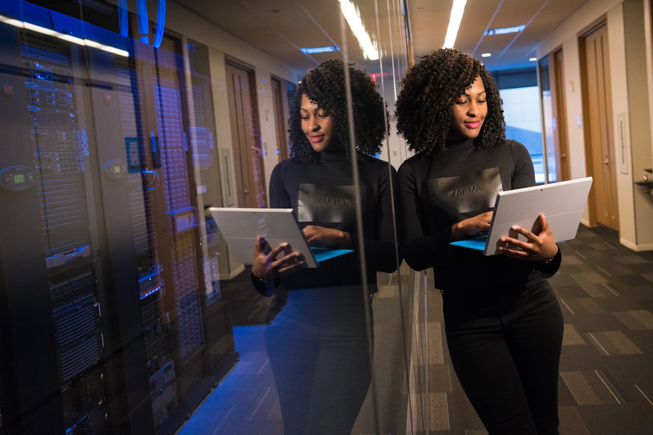 why-choose-us African American woman standing in modern office using laptop, reflecting professionalism and technology engagement.